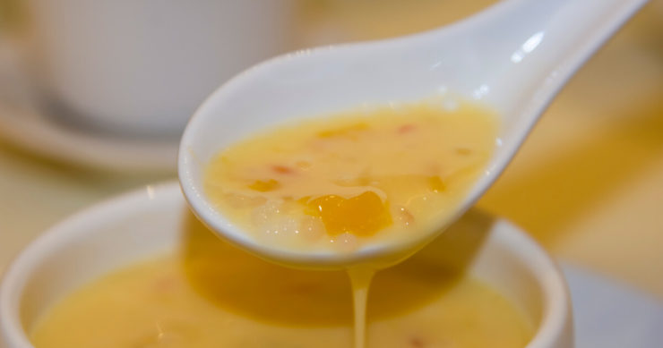 マンゴー・タピオカ・ココナッツミルクが入った香港のスイーツ「ヨンジーガムロウ」をスプーンですくっている画像